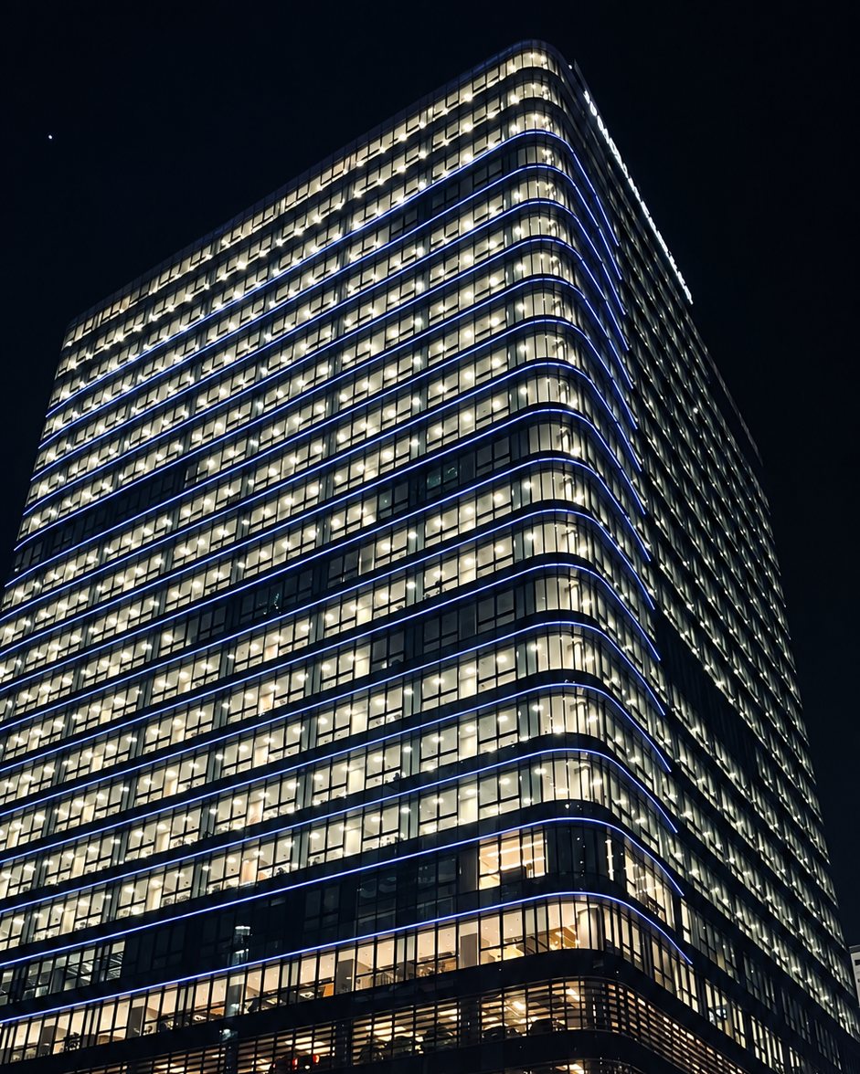 A glass office tower lit up at night